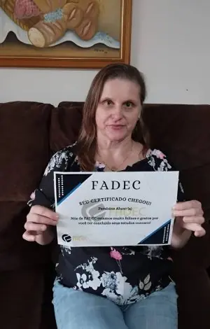 Aluna da FADEC em casa com seu cartão de conclusão